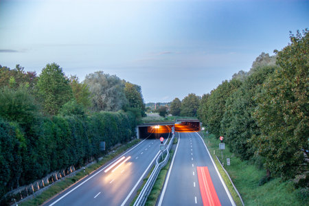 Long exposure shot of a multi-lane highway at dusk, with vibrant red light trails from vehicles...