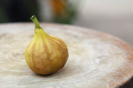 Ripe yellow fig fruit on wooden chopping block, blur background.の写真素材