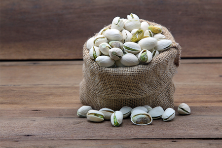 Pistachio nuts in burlap sack on wooden background, Food.の写真素材