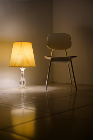 A interior photograhy of a room corner which placed with wood chair and bedside lamp together on the white floor in the warm tone and nigt time feeling.の写真素材
