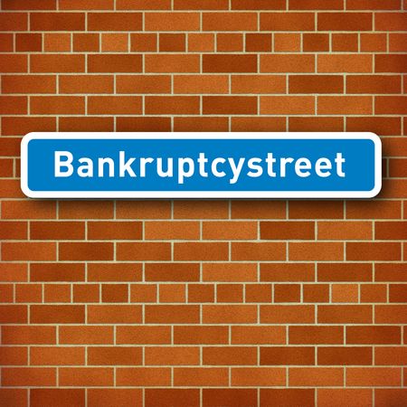 Streetsign or roadsign in blue and white with the name Bankruptcy street on a brown brick wallの写真素材