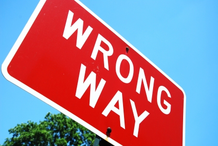 wrong way road sign on a blue sky backgroundの写真素材
