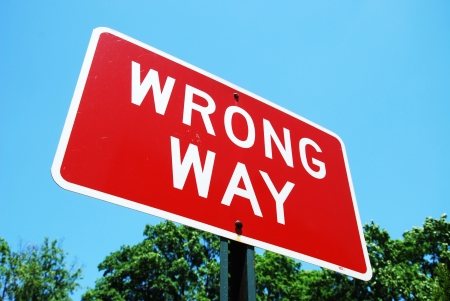 wrong way road sign on a blue sky backgroundの写真素材