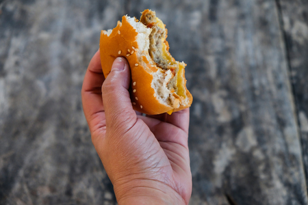 Hands holding a hamburger isolated on wood backgroundの写真素材