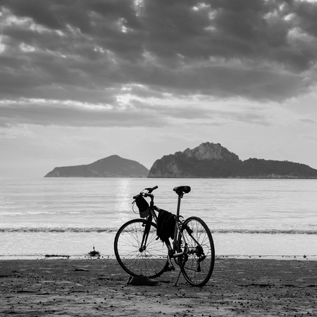 silhouette of a bike standing by the seaの写真素材