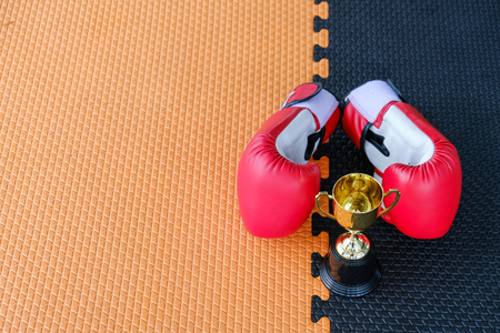 Golden trophy cup with red boxing gloves on black and orange backgroundの写真素材