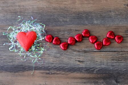 Heart shaped chocolate candy with red wrappings on wood backgroundの写真素材