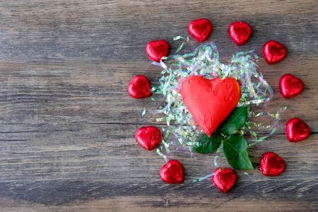 Heart shaped chocolate candy with red wrappings on wood backgroundの写真素材