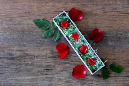 Heart shaped chocolate candy  in box and rose on wood backgroundの写真素材