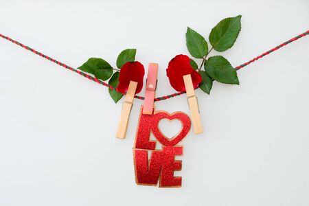 Red word LOVE  and rose on rope with clothespins, on a white  backgroundの写真素材