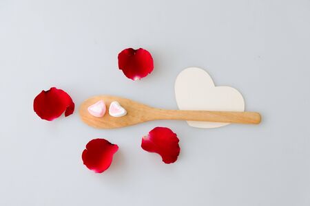 Two marshmallow shape heart on wood spoon and rose isolated on white backgroundの写真素材