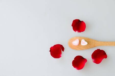 Two marshmallow shape heart on wood spoon and rose isolated on white backgroundの写真素材