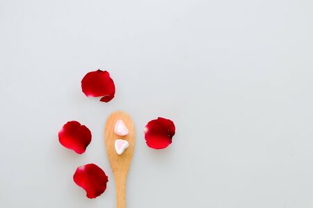 Two marshmallow shape heart on wood spoon and rose isolated on white backgroundの写真素材