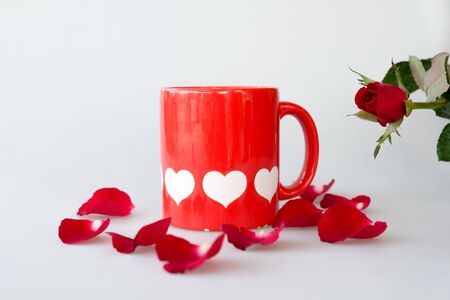 Printed white hearts on red coffee cup and rose isolated on white backgroundの写真素材