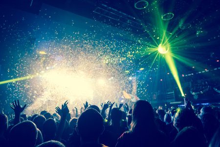 shiny confetti during the concert and the crowd of spectators with their hands upの写真素材