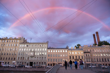 Rainbow in the sunset sky over Saint Petersburg. View of the Fontanka River embankment and Gorstkin Bridge with pedestriansの写真素材