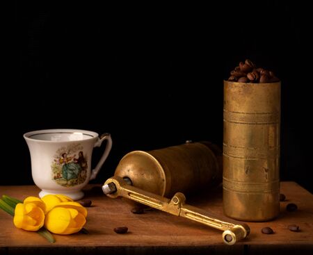 Old coffee grinder with cup and coffee beans on a wooden boardの写真素材