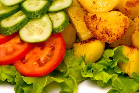 Fried potatoes with fresh cucumbers and tomatoes on studio white.の写真素材