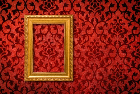Gold frame on a vintage red wall background の写真素材