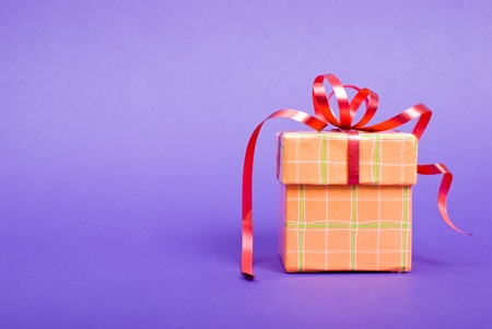 Single orange gift box with red ribbon on blue background.の写真素材