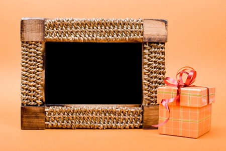 Photo frame and gift box with ribbon on yellow background.