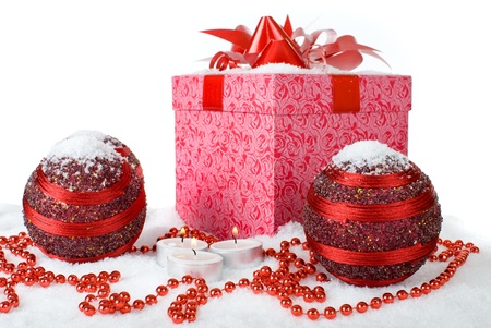 Christmas gift box in the snow with red balls and candlesの写真素材