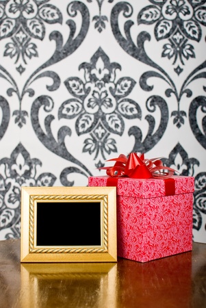Golden photo frame and present box on tableの写真素材