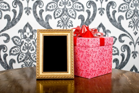 Golden photo frame and present box on tableの写真素材