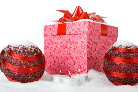 Christmas gift box in the snow with red balls and candlesの写真素材