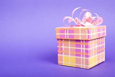 Single yellow gift box with pink ribbon on blue background.の写真素材
