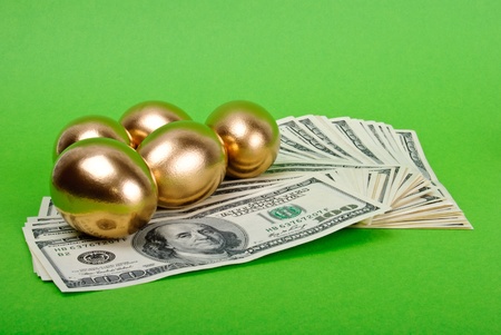 Golden eggs. A symbol of making money and successful investment on green backgroundの写真素材