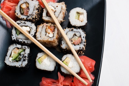Sushi on a black plate on white table.の写真素材