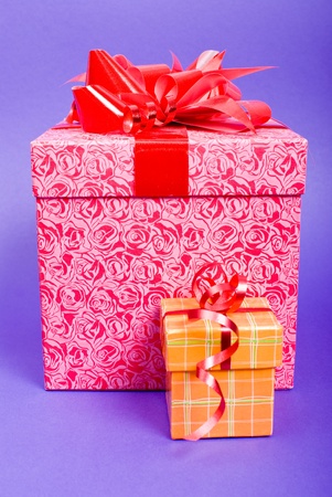 Orange and pink gift box with red ribbon on blue background.の写真素材