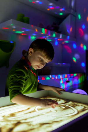 The boy draws sand in the sandの写真素材