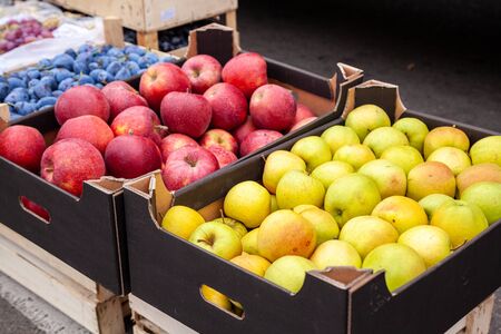 Crates of apples at a farmers market. Cardboard boxes with various kinds of apples in the local agricultural market. Fresh apples directly from the tree are sold on the open market.の写真素材
