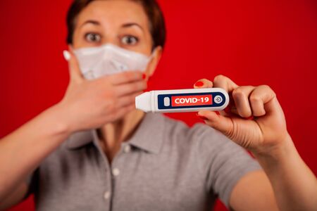 A woman in a panic from infection with the coronavirus COVID-19. A woman in a mask on a red...