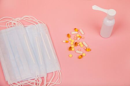 Medical mask, pills and spray for the treatment of throat on a pink background, concept of...