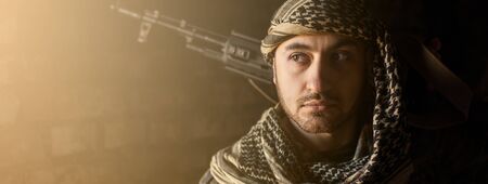 Arab male soldier in a headdress from the national keffiyeh with a weapon in his hands Muslim man with a gun on a black backgroundの写真素材
