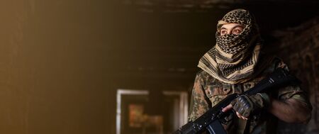 Arab male soldier in a headdress from the national keffiyeh with weapons in his hands. Muslim with firearms against the background of the brick wallの写真素材
