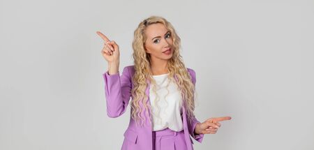Pretty blonde woman smiles, gives advice, pointing sideways left and right, showing a good choice promotes two products, both waysの写真素材