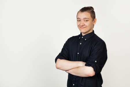 A handsome young guy in a black shirt with a smile on his face crossed his arms over his chest....