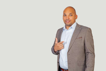 Portrait of young african american guy businessman pointing with index finger at camera and smiling brightly. Standing on a gray backgroundの写真素材
