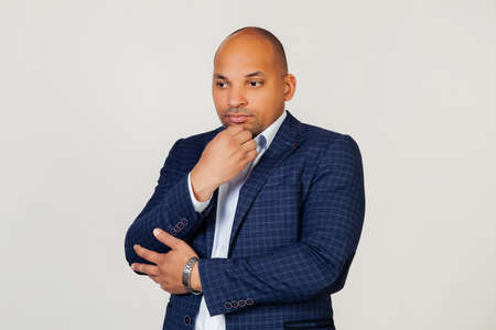 Portrait of an unhappy young African American guy businessman, thinking looking tired and bored with depression problems with crossed arms. Standing on a gray backgroundの写真素材