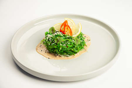 Chuka salad on a plate. Ingredients Marinated seaweed, peanut sauce, lemon, chili, sesame mix. For...