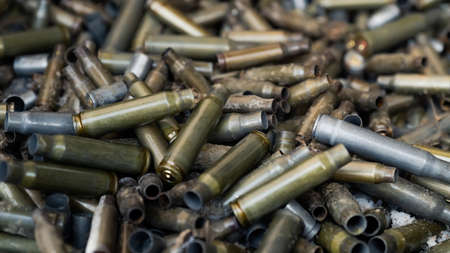 Empty carbine or rifle cartridges. A large number of cases. Background of brass ammunition cartridges to illustrate armed conflict, war or shootingの写真素材