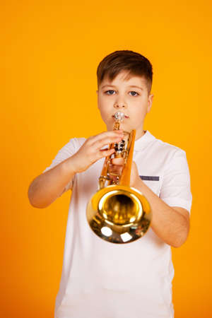 A boy plays the trumpet. Beautiful teenager boy plays trumpet musical instrumentの写真素材