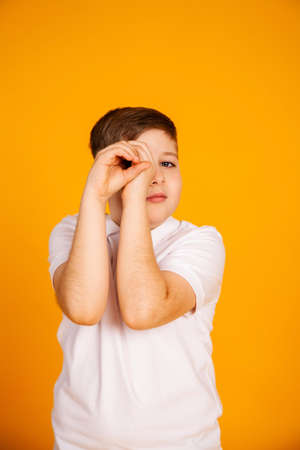 The boy looks like through binoculars. Hands foldedの写真素材