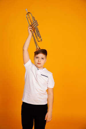 A boy holds a trumpet with a musical instrument on his head