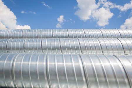 Ventilation pipes against the blue sky. Steel pipes, parts for the construction of air ducts for an industrial air conditioning system in a warehouse. Industrial ventilation equipmentの写真素材