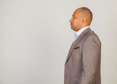 Young African American man standing looking to the side. Serious African man male, standing in profile, looking to the side, posing for a photo. Confident black guy looking forward to copy spaceの写真素材